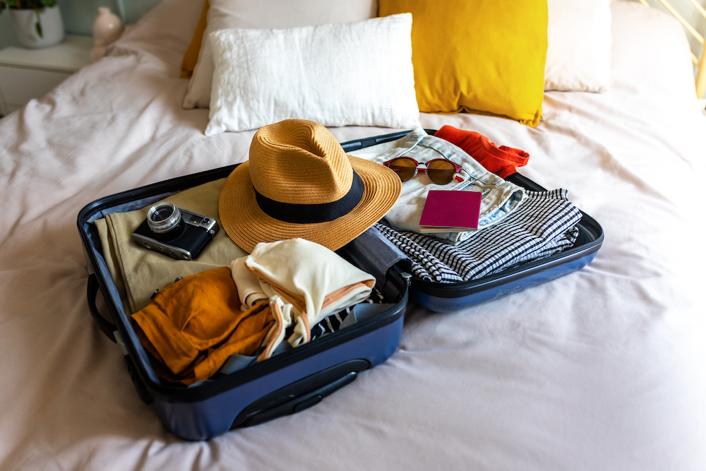 open suitcase on a bed, packed for a beach vacation 